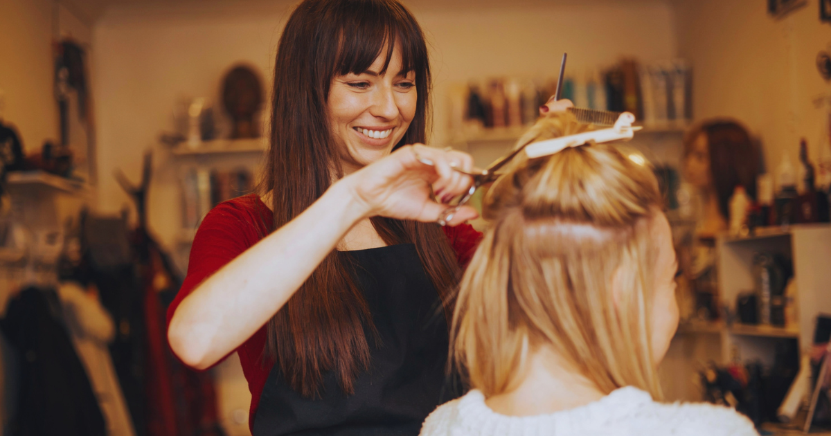 Hairstylist cutting a client’s blonde hair in Camp Hill, PA